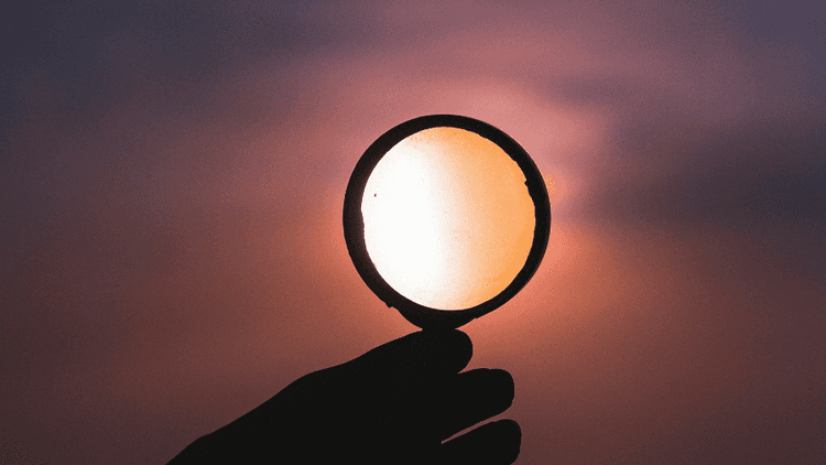 magnifying glass revealing a vibrant sunset sky, symbolizing clarity and discovery