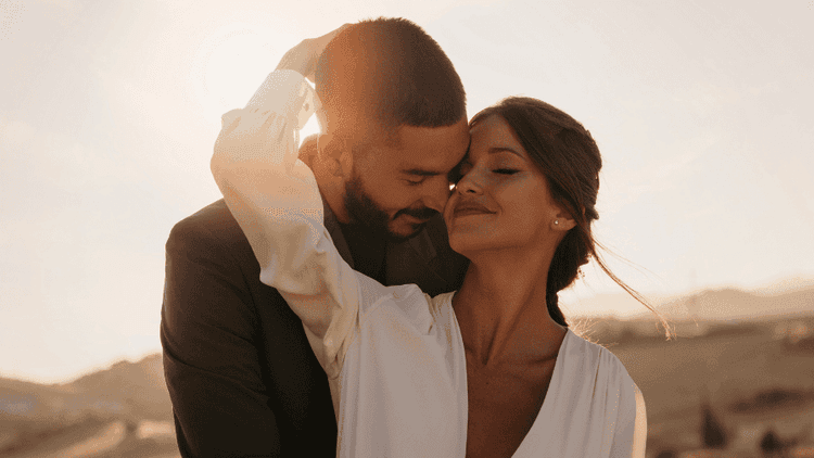 Happy couple embracing with eyes closed during a sunrise, symbolizing love and connection in nature